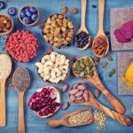 Verschiedene Superfoods wie Beeren, Nüsse, Samen und Gewürze auf einem Holztisch – natürliche Quellen für Vitamine, Mineralstoffe und Antioxidantien.