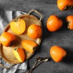 Foto: <a href="https://stock.adobe.com/de/images/tray-with-ripe-persimmons-on-grey-background-top-view/237217591" target="_blank" rel="noopener">Pixel-Shot / stock.adobe.com</a> Kaki