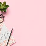 Menopause, Wechseljahre (Notebook with text DEAR MENOPAUSE LEAVE ME ALONE, pen, eyeglasses and flowerpot on pink background)