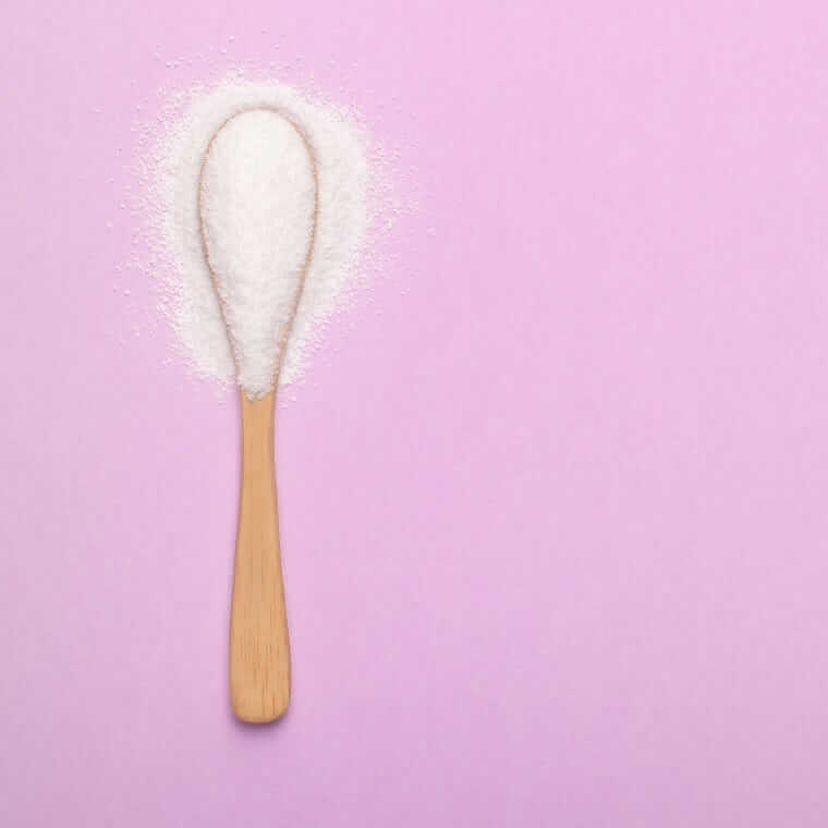 Zuckerersatzstoffe (A spoon with natural sweetener lies on a pink background)