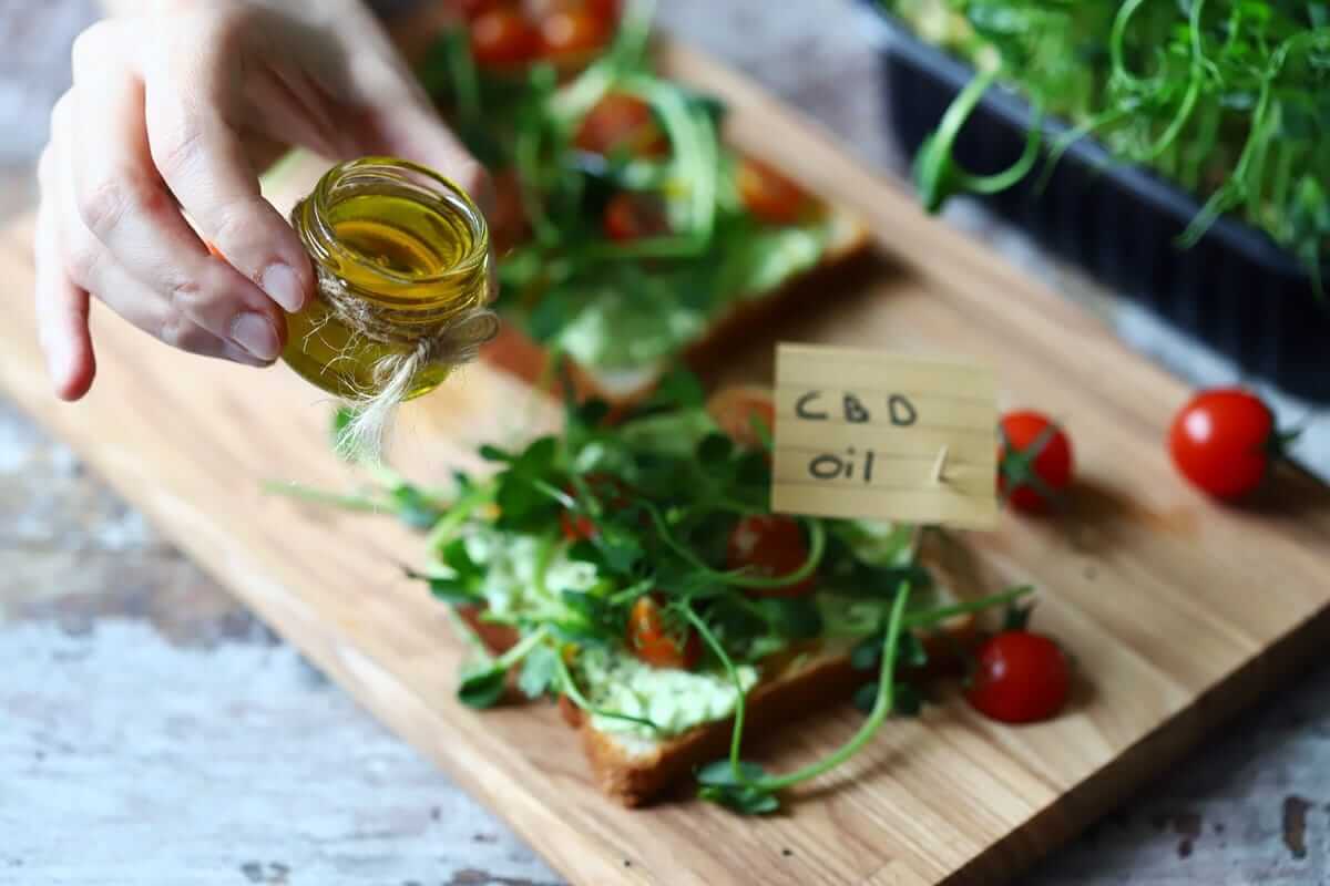 CBD-Avocado-Tomaten-Salat-Rezept (Selective focus. Healthy toasts with microgreens and cbd oil. Cannabidiol concept. CBD oil. Cbd food.)