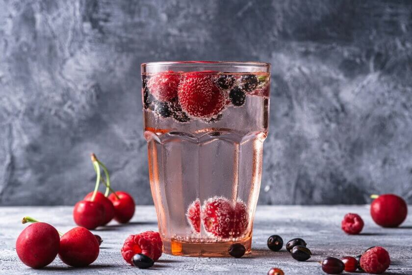 Glas mit Kirschen und Beeren – Kirschen können den Harnsäurespiegel bei Gicht senken