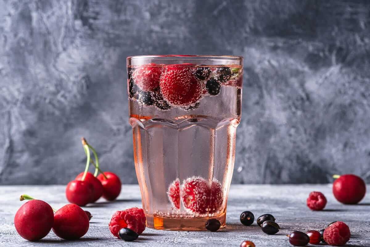 Glas mit Kirschen und Beeren – Kirschen können den Harnsäurespiegel bei Gicht senken