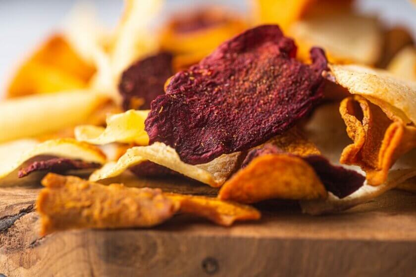 vegane Chips / Vegetable chips laid on a wooden board close up