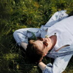 Longevity Ernährung (Person mit Sonnenbrille liegt entspannt im Gras – Symbolbild für bewusstes Leben und gesunde Lebensweise)