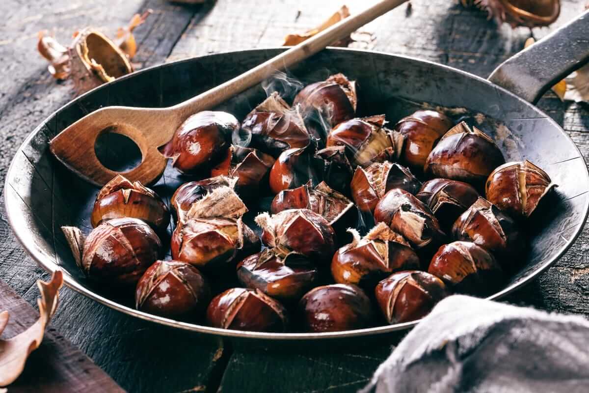 Maronen – das herbstliche Superfood mit Tradition Maronen, Esskastanien (Geröstete Maronen in einer Pfanne mit Holzlöffel, frisch aufgeplatzt und dampfend, als herbstliche Spezialität serviert.)