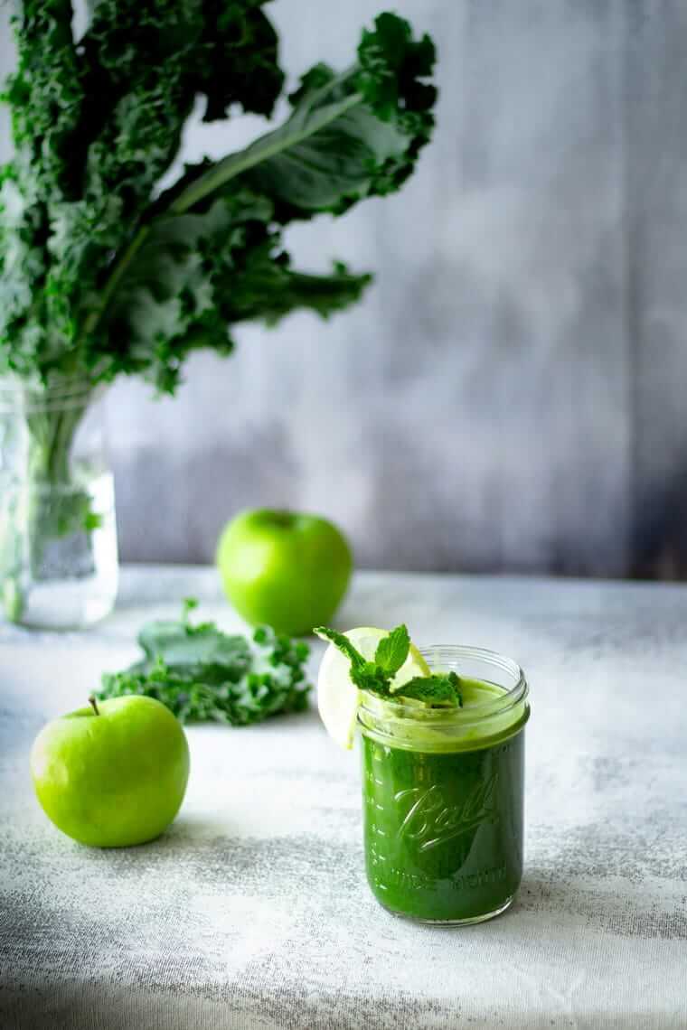Grüner Smoothie aus Grünkohl, Apfel, Minze und Zitrone in einem Glas – gesundes Getränk voller Vitamine, Antioxidantien und Nährstoffe für schöne Haut.