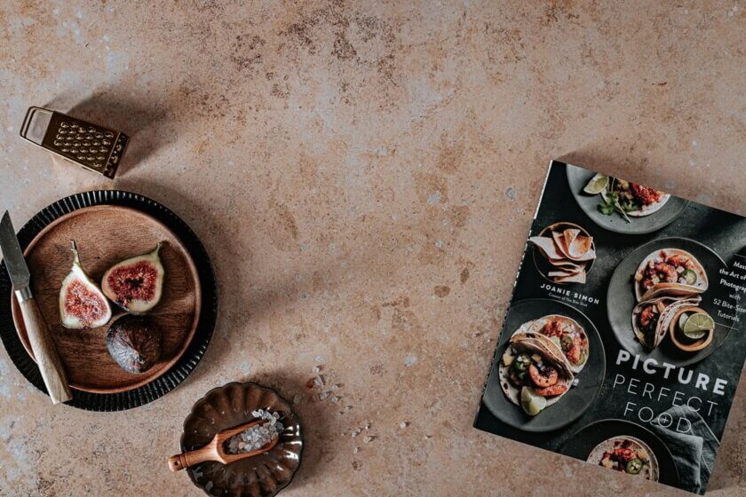 Food-Blog / Food-Fotografie mit aufgeschnittenen Feigen, Salz und dem Buch „Picture Perfect Food“ auf Steinuntergrund – Symbol für professionelle Bildoptimierung im Ernährungsblog.