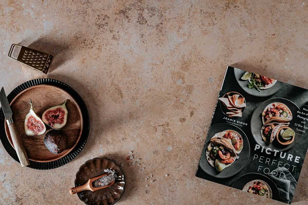 Bilddateien für den Food-Blog optimieren – schneller hochladen, besser präsentieren Food-Blog / Food-Fotografie mit aufgeschnittenen Feigen, Salz und dem Buch „Picture Perfect Food“ auf Steinuntergrund – Symbol für professionelle Bildoptimierung im Ernährungsblog.