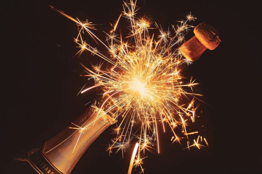 Top 10, Top Artikel, Beiträge / Champagnerflasche mit sprühender Wunderkerze und fliegendem Korken vor dunklem Hintergrund – Symbol für Silvester, Neuanfang und festliche Stimmung.