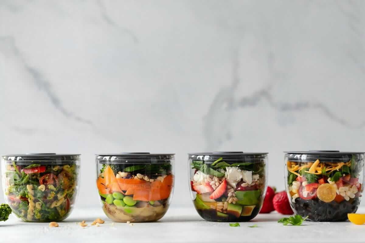Warum Lieblingsgerichte nachhaltiger sind als neue Rezepte Lieblingsgerichte / Vier Glasgefäße mit vorbereiteten Salaten in verschiedenen Variationen – Meal Prep mit Abwechslung