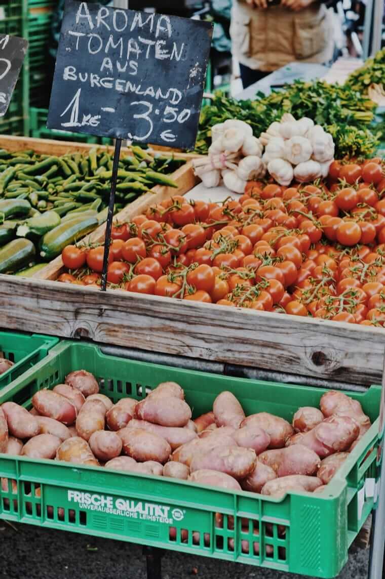 Wie viel Planung braucht nachhaltige Ernährung wirklich? Essensplanung / Gemüsestand auf dem Wochenmarkt mit Tomaten, Zucchini und Kartoffeln – spontan einkaufen mit Überblick