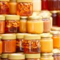 Honig kaufen / Verschiedene Honiggläser in unterschiedlichen Farben und Konsistenzen auf einem Marktstand — von hell-golden bis dunkelbraun