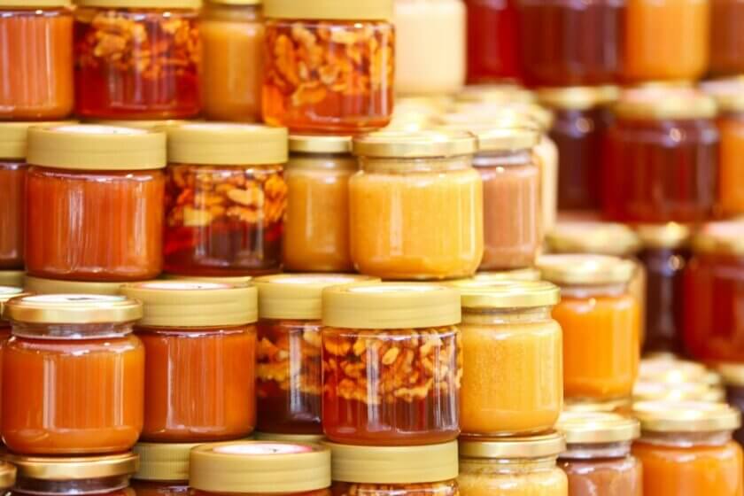 Honig kaufen / Verschiedene Honiggläser in unterschiedlichen Farben und Konsistenzen auf einem Marktstand — von hell-golden bis dunkelbraun