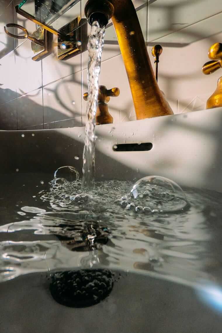 Warum Leitungswasser die unterschätzte Nachhaltigkeits-Entscheidung ist Blick von unten auf fließendes Leitungswasser am Küchenhahn – sauberes Trinkwasser aus der Leitung