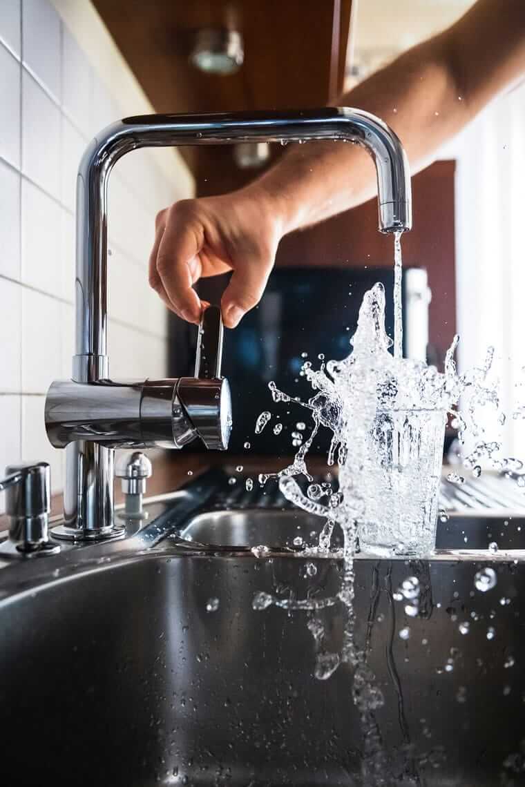 Warum Leitungswasser die unterschätzte Nachhaltigkeits-Entscheidung ist Glas wird mit frischem Leitungswasser am Küchenhahn gefüllt – direkt verfügbar und kontrolliert