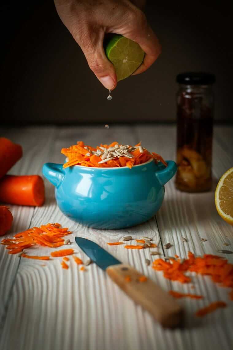 Geschmacksschichten / Hand drückt Limette über Karotten-Sesam-Bowl