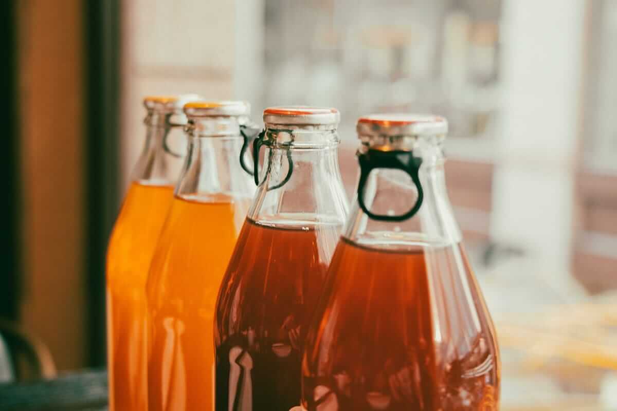 Trinkessige im Trend: Was hinter Shrubs & Co. steckt Selbst gemachte Trinkessige in Bügelflaschen vor hellem Fenster – einfache Zubereitung zum Nachmachen